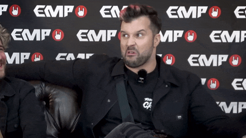 a man is sitting in front of a wall that says empo