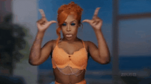 a woman in an orange bra is dancing with her arms outstretched