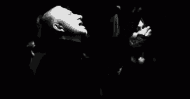 a black and white photo of a man and a woman in a dark room .