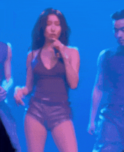 a woman is singing into a microphone while dancing on stage