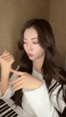 a woman with long hair is sitting at a piano and making a funny face .