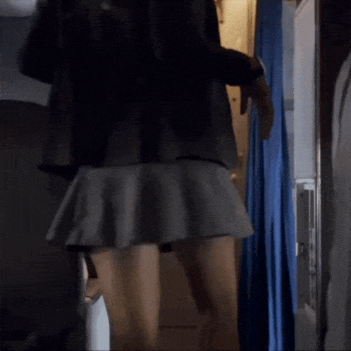 a woman in a short skirt is standing in a room