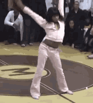 a woman is dancing on a basketball court while a crowd watches .