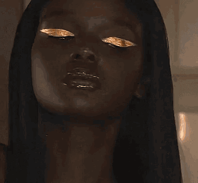a close up of a woman 's face with gold paint on her face .