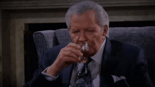 an older man in a suit and tie is holding a glass of whiskey