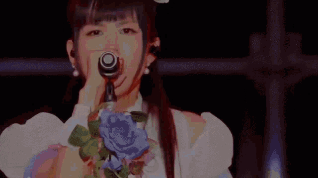 a woman is singing into a microphone and her hair is blowing in the wind