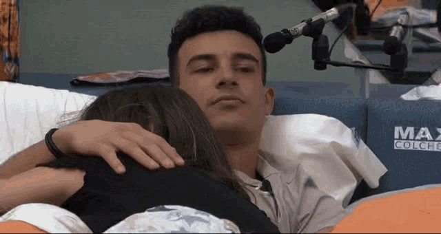 a man and a woman are hugging in front of a max colche sign