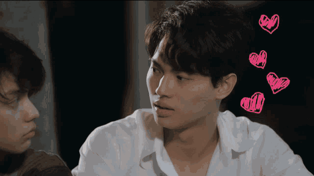 a man in a white shirt has pink hearts drawn on his head