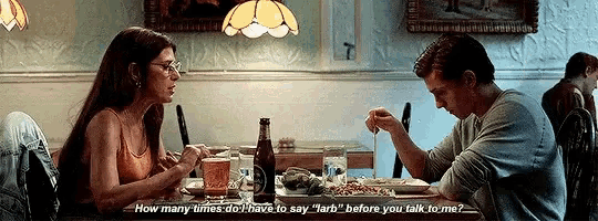 a man and a woman are sitting at a table in a restaurant talking to each other