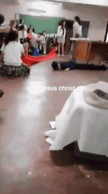 a group of people are in a classroom with jesus christ written on the floor .