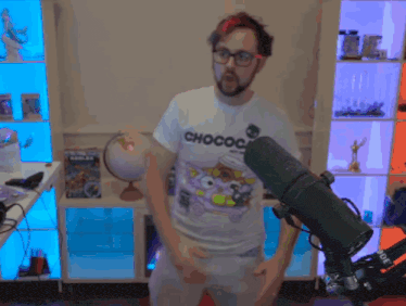 a man in a chococat t-shirt is standing in front of a microphone