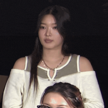 a woman wearing a white off the shoulder top and a necklace