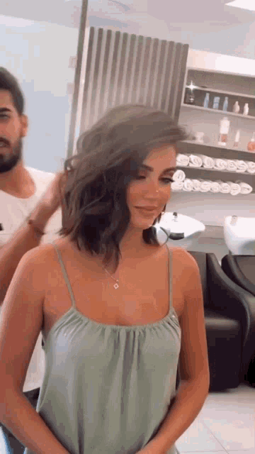 a woman in a green tank top is getting her hair cut in a salon .