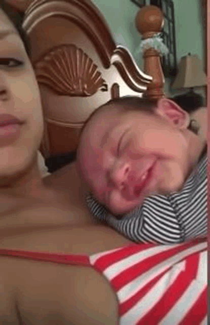 a woman is holding a crying baby on her shoulder .