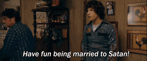 a man is standing in a living room with the words have fun being married to satan