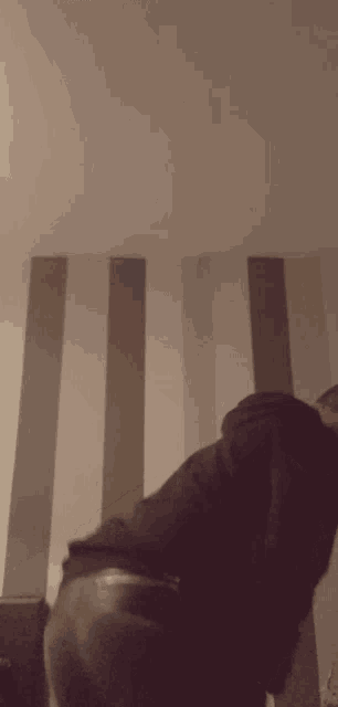 a man in a black jacket is standing in front of a wall with stripes