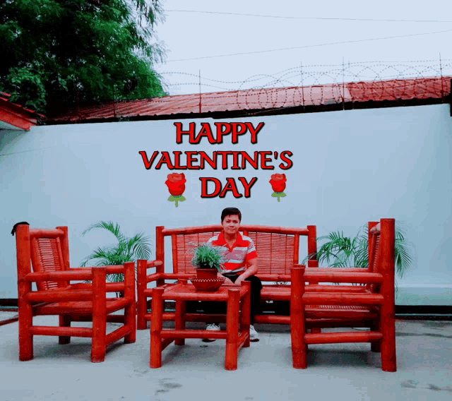 a man sits on a wooden bench in front of a wall that says happy valentine 's day