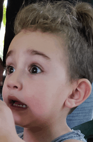 a close up of a child 's face with a very surprised look on his face