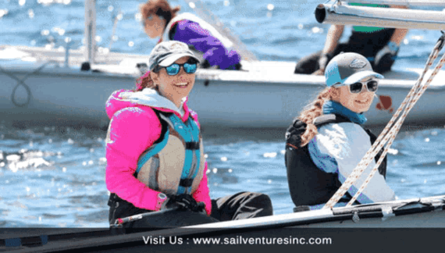 two women are sitting in a boat with the website sailventuresinc.com visible
