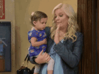 a woman is holding a baby in her arms and covering her mouth .