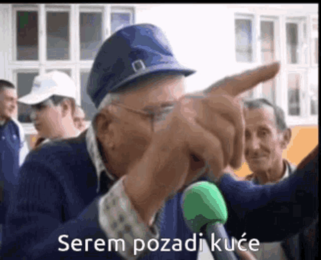 a man speaking into a microphone with the words " serem pozadi kuce " written below him