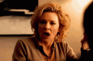 a woman is making a funny face while sitting at a table with a man .