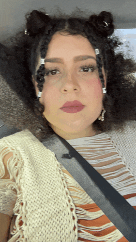 a woman wearing a white sweater and a black seat belt