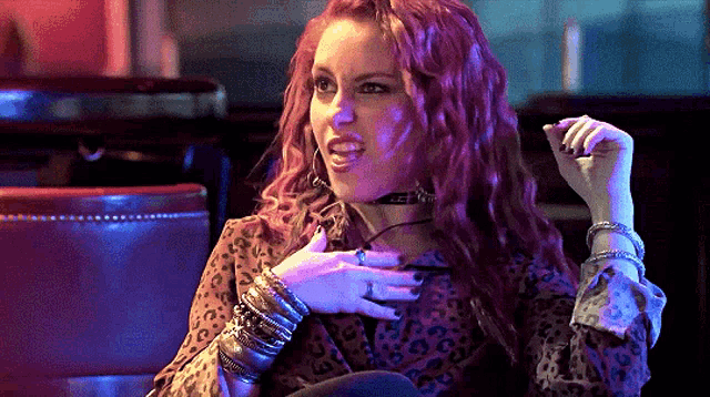 a woman with red hair is sitting in a chair with her hands on her chest