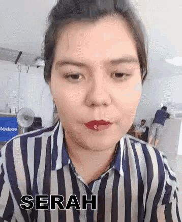 a woman in a striped shirt is making a funny face and the word serah is on the bottom of her shirt .