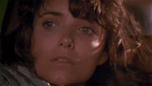 a close up of a woman 's face with a surprised look on her face in a dark room .