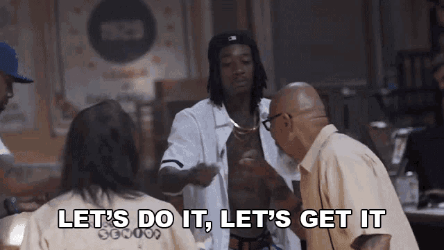 a man in a white shirt says let 's do it let 's get it in front of a group of people