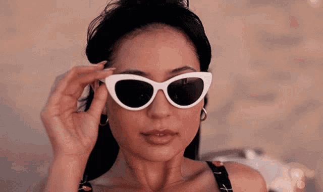 a woman wearing a pair of white cat eye sunglasses .