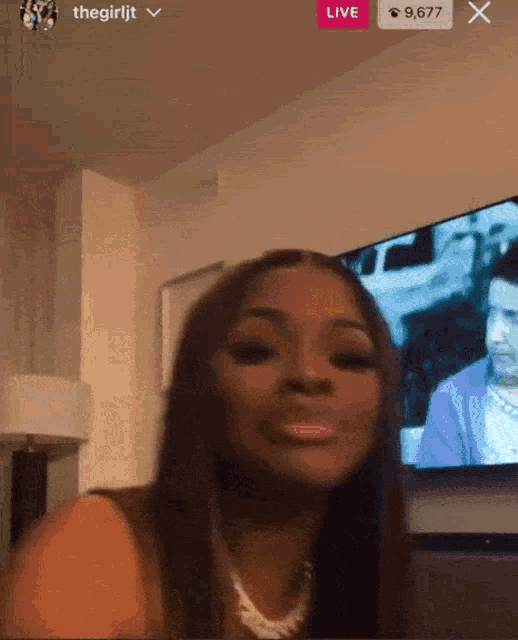 a woman is sitting in front of a television while a live stream is going on .