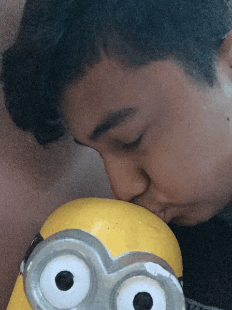 a young man kisses a yellow toy with big eyes