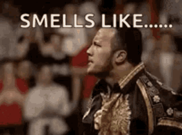 a man in a black and gold jacket is standing in front of a crowd and says `` smells like ... '' .