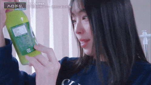 a woman is holding a green bottle that says ocha norma