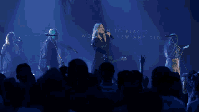 a group of people singing in front of a sign that says " e chased the peaks through darkness to the sea "