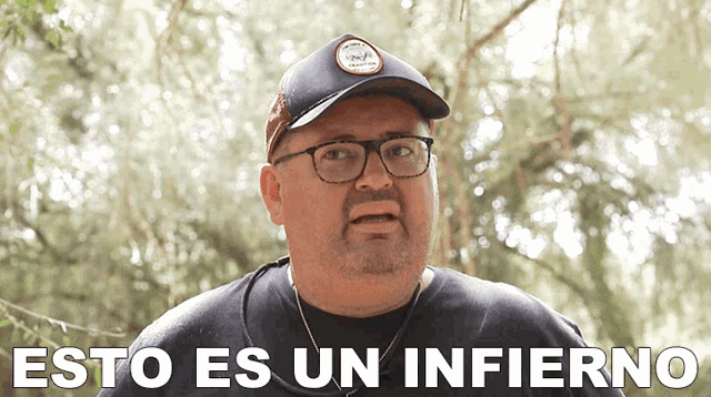 a man wearing glasses and a hat with the words esto es un infierno behind him
