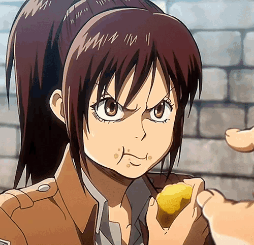 a girl with a ponytail is eating a piece of food from a person 's hand