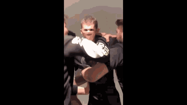 a man in a black shirt is being held by another man in a room .