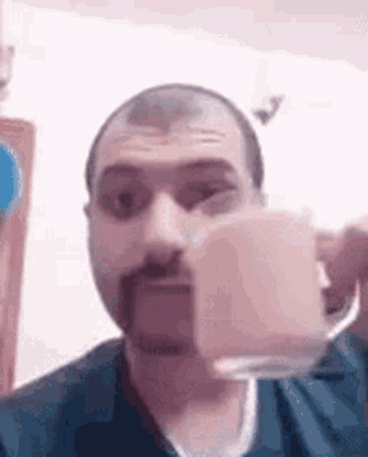 a man with a beard is holding a cup of coffee in his hand .