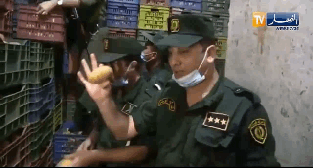 a group of police officers are standing in front of crates with a tv news channel behind them