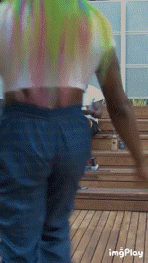 a person wearing a tie dye shirt and blue jeans is walking on a wooden deck ..