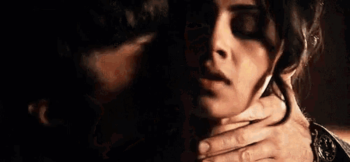 a man is holding a woman 's neck while kissing her .