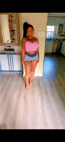 a woman in a pink top and blue shorts stands in a room
