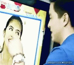 a man in a blue shirt is looking at a picture of a woman on a screen that says aldubmode tumblr