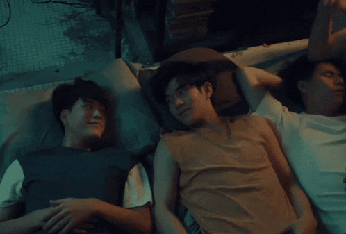 three young men are laying on a bed together