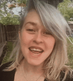a woman with gray hair is smiling and wearing a black shirt .