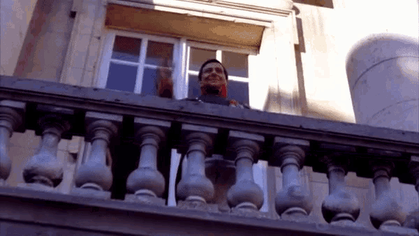 a man stands on a balcony looking out the window