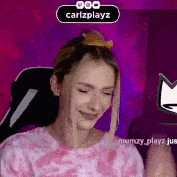 a woman in a pink shirt is sitting in front of a computer screen .
